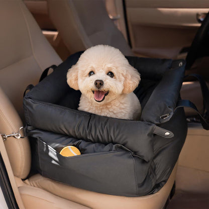A fluffy small Bichon Frise sitting happily in a black multifunctional pet car seat carrier with a side storage pocket holding a toy ball, keeping pet essentials accessible during travel and outdoor trips.